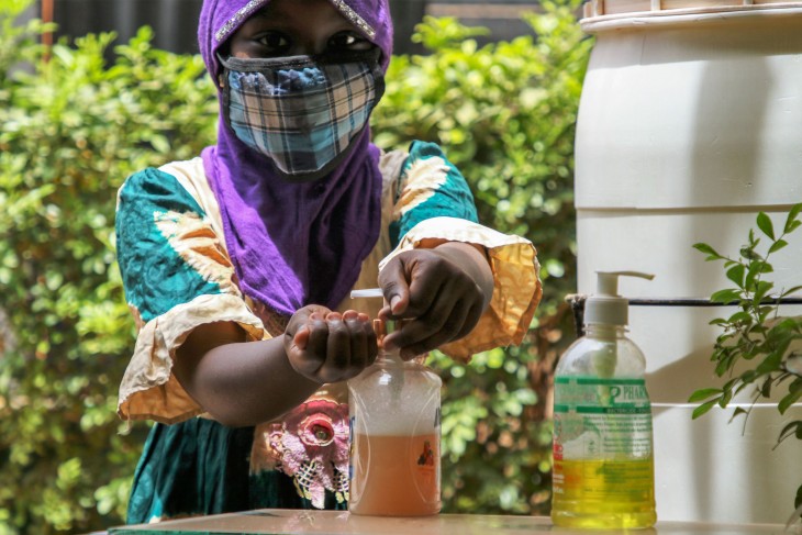 マスクをつけ、手を消毒する黒人の少女