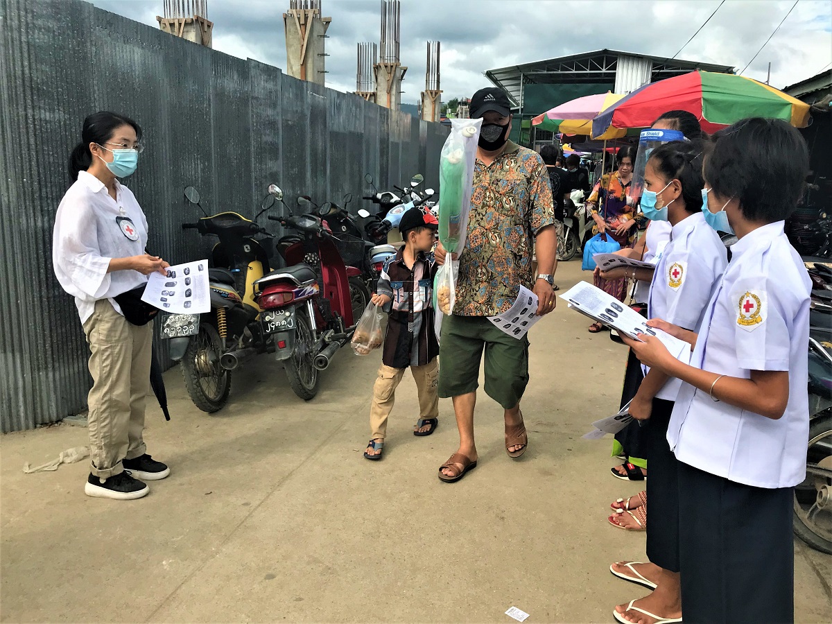 ミャンマー赤十字社と共に、新型コロナウイルス感染症に関するパンフレットを配る扇割(左)