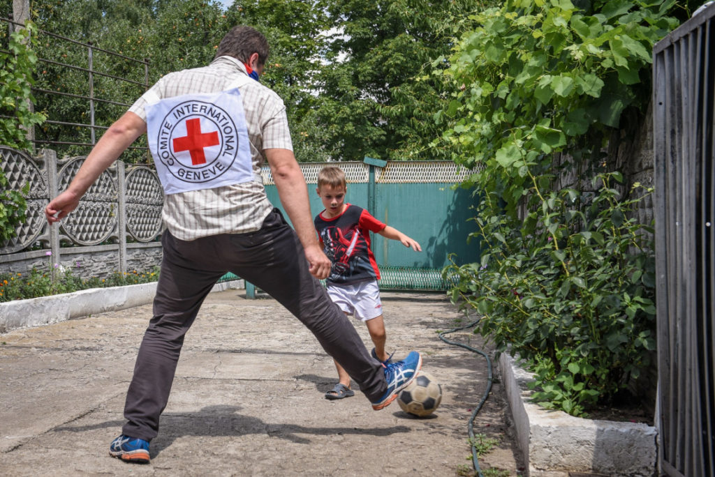 サッカーボールで遊ぶ子供とICRC職員