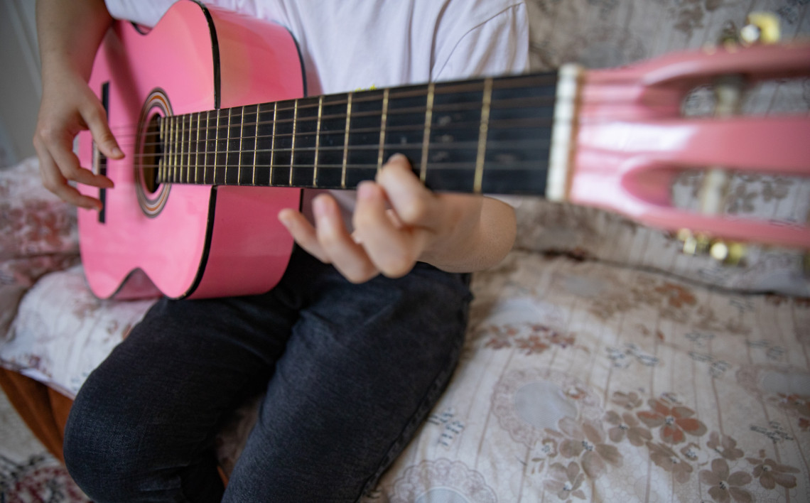 椅子に座りピンク色のギターを奏でる少女