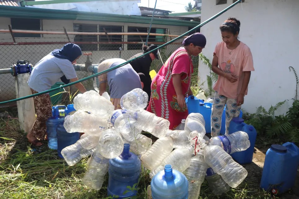 Residents at the Sagonsongan temporary shelter in Marawi queue to get clean water.